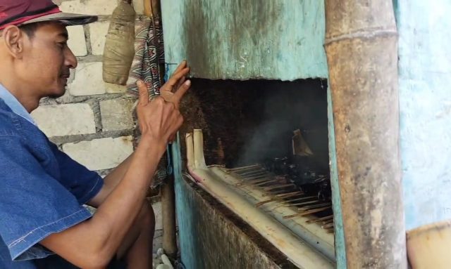 Seorang warga saat panggang ikan asap. (ist)